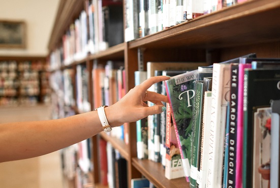 Person selecting book from shelf.